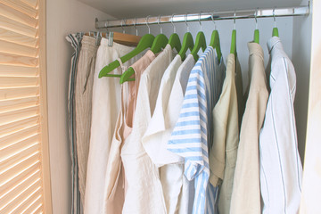 summer wardrobe with linnen clothes on green hangers