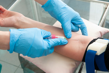 Hand of nurse or doctor in blue gloves taking blood sample from a patient in the hospital.