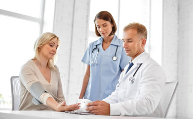 Fototapeta premium medicine, healthcare and medical exam concept - doctor measuring patient woman's arterial blood pressure at hospital