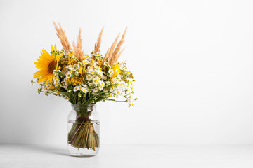 Field flowers in a glass vase. Summer bouquet of flowers on the white background