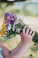 a beautiful girl in a striped dress holding a bouquet of wild flowers
