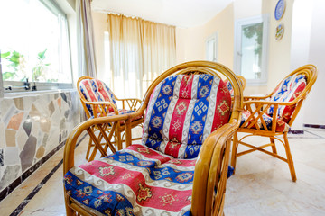 Rattan chair with soft cushions with oriental pattern.