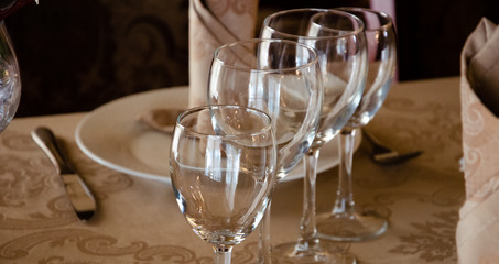 Restaurant vintage, cutlery, glasses on the table, bar, bottles, large candles on a white tablecloth, sliced fruit with powdered sugar