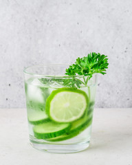 Glass of cool infused water with fresh cucumber, lime and parsley, (lemonade, cocktail). Detox drink, health care, fitness, diet concept.