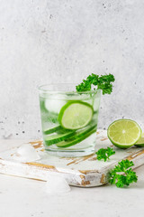 Glass of cool infused water with fresh cucumber, lime and parsley, (lemonade, cocktail). Detox drink, health care, fitness, diet concept.