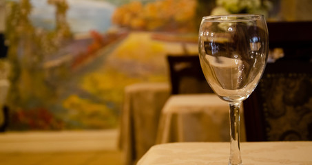 Restaurant vintage, cutlery, glasses on the table, bar, bottles, large candles on a white tablecloth, sliced fruit with powdered sugar