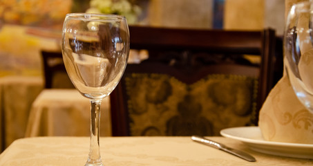 Restaurant vintage, cutlery, glasses on the table, bar, bottles, large candles on a white tablecloth, sliced fruit with powdered sugar
