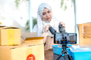 Thai young muslim online sell or trader selling product online via live with mobile phones in the online society medias. She is presenting, demonstrating and offering products to customers.