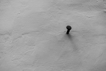 Big nail in white textured wall
