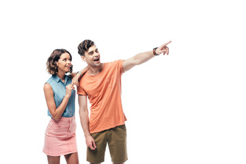 Fototapeta premium cheerful man looking away and pointing with finger near smiling woman isolated on white