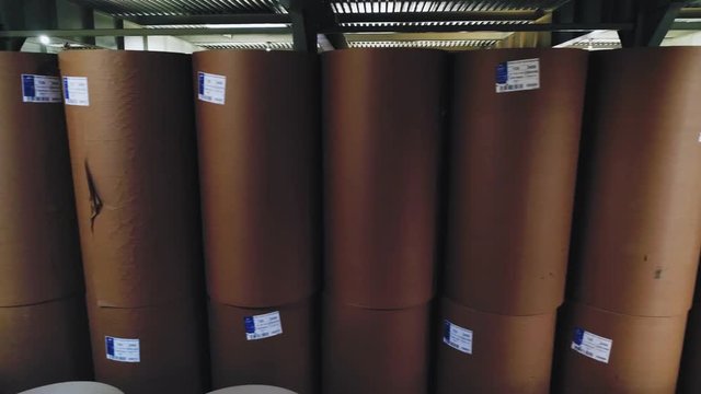 cardboard paper rolls stacked in large workshop at factory