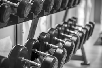 Fototapeta na wymiar Black dumbbell set. Close up many metal dumbbells on rack in sport fitness center , Weight Training Equipment concept.