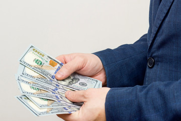 Hands of businessman counting dollar bills. Concept of savings, salary, payment and funds. Man counts cash bills