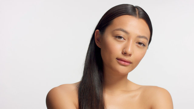 mixed race model with straight hair watching to the camera. Ideal skin, natural glowy makeup