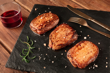Sirloin beef steaks with salt, rosemary, and red wine on a black slate plate
