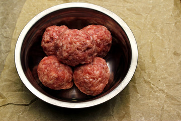 raw mince meat bals in a metal bowl on craft papper