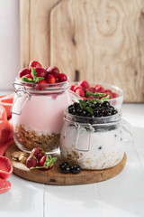 Healthy breakfast cereal with homemade strawberry and blueberry in glass jar on wooden board in home kitchen