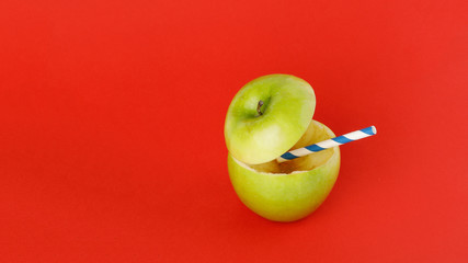 Healthy Green Cut Apple recyclable paper straw juice drink idea concept on red background