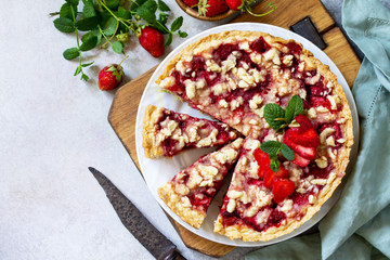 Delicious summer dessert strawberry pie with crumble, sweet delicious holiday cake with strawberry on a light stone or slate table. Top view flat lay.