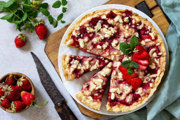 Delicious summer dessert strawberry pie with crumble, sweet delicious holiday cake with strawberry on a light stone or slate table. Top view flat lay.
