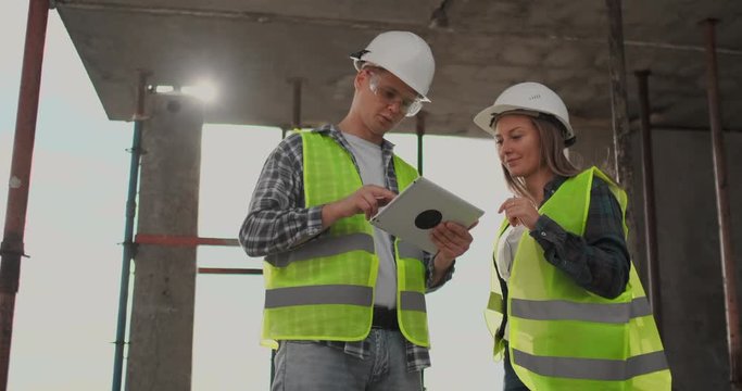 Engineers or architects have a discussion at construction site looking through the plan of construction. contre jour. Engineers or architects have a discussion.