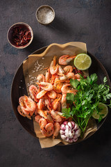 Raw prawns in a cooking pan with ingredients for preparation fried shrimps on a dark background top view
