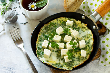 Breakfast background. Fried eggs with spinach, feta cheese on stone table. Free space for your text.