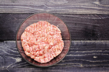 raw minced meat in a glass bowl om black wooden desktop surface flat lay copy space. Burger. 