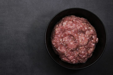 flat lay minced meat in dip black dish on black surface. Burger. 