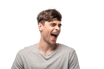 excited young man laughing while looking away isolated on white