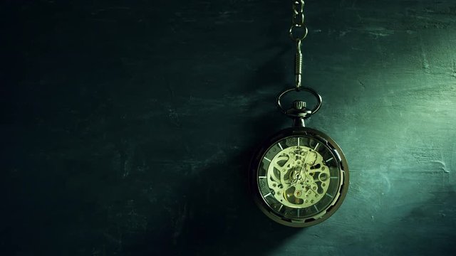 Time lapse pocket watch hanging on black chalkboard and sunlight in morning. Concept of time and education.