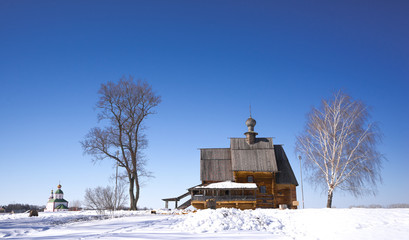 Old wooden church in a field between two trees. Travel to Russia