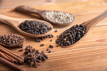 close up chille pepper in wooden spoon surround with spice powder on wooden table