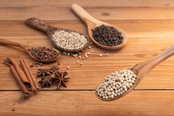 close up white pepper in wooden spoon surround with spice powder on wooden table