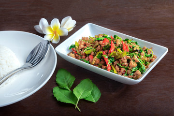 Rice with fried pork with basil leaf in white dish on dark brown table