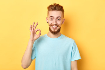 Successful excited man with funny moustache is standing isolated on a yellow background and shows...