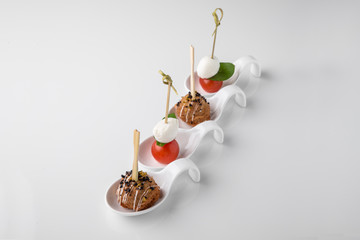 Assorted canapes on caprese skewers with cherry, mozzarella and basil and meatballs. Beautifully...