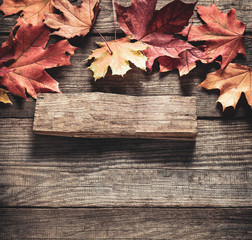Obraz premium autumn background with signboard, orange leaf on old grunge wood deck, copy place for inscription, Top view, tablet for text.