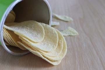 Crispy potato chips in can on wooden table background