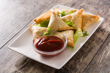 Samsa or samosas with meat and vegetables on wooden table. Traditional Indian food. 