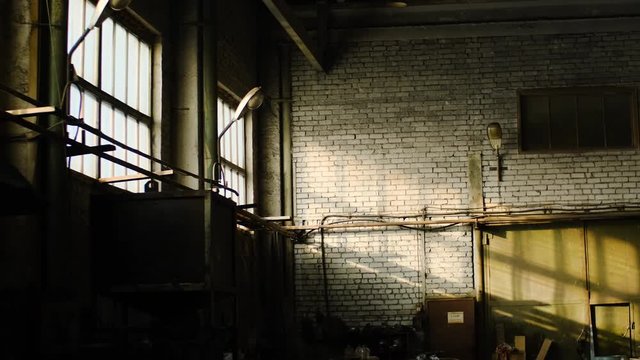 Old abandoned warehouse of industrial enterprise. Stock footage. Small abandoned room of old warehouse cluttered and illuminated by sun rays making their way out of windows