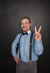 Handsome business man with victory gesture on blackboard