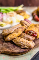 Pieces of fresh raw chicken parts on a cutting board on wooden old plank or table with blur Thai herbs and whole chicken. Chicken with Thai herbs prepared for cooking soup.