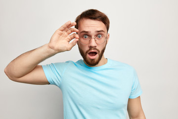 surprised man dressed casually, stares through glasses, being surprised with news, information Male doesn t believe his own luck, isolated over white background.Really Are you kidding 