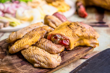 Pieces of fresh raw chicken parts on a cutting board on wooden old plank or table with blur Thai herbs and whole chicken. Chicken with Thai herbs prepared for cooking soup.