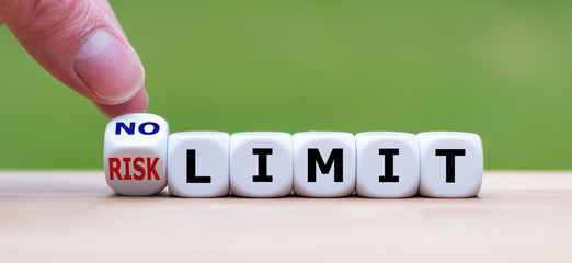 Hand turns a dice and changes the expression "RISK LIMIT" to "NO LIMIT"
