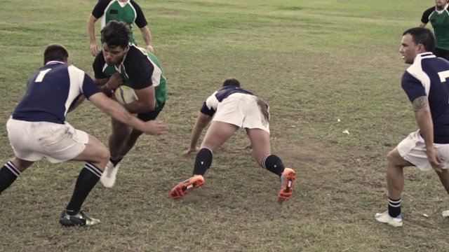 Rugby players tackling for ball possession during the game. Professional players playing rugby on field.