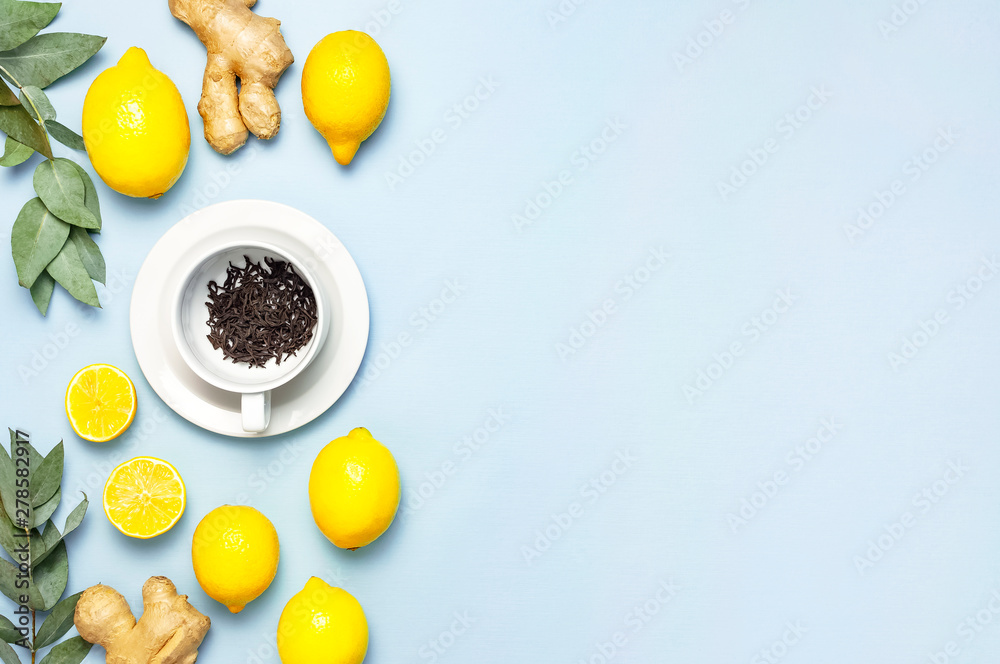 Wall mural Creative food concept. Fresh ginger root, cup tea with brewing inside, lemon, eucalyptus leaves on blue background. Flat lay top view copy space. Minimalistic style seasoning spice ingredient for tea