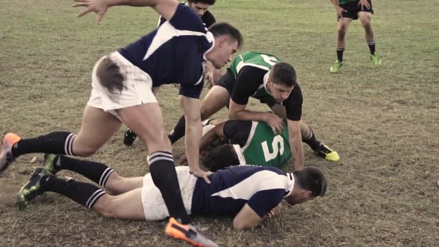 Rugby players tackling for ball possession at sports arena. Rugby players in action during a championship match.