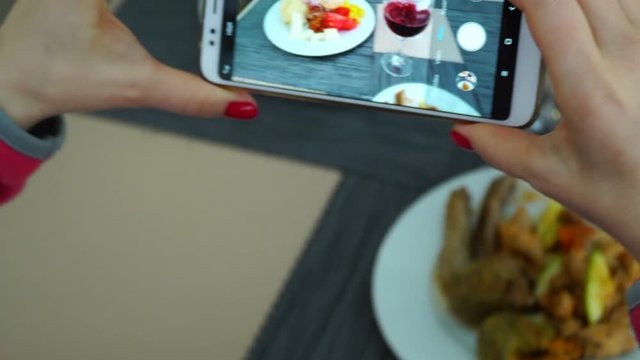Shooting on a smartphone for social networks. A woman photographs food and a glass of wine.